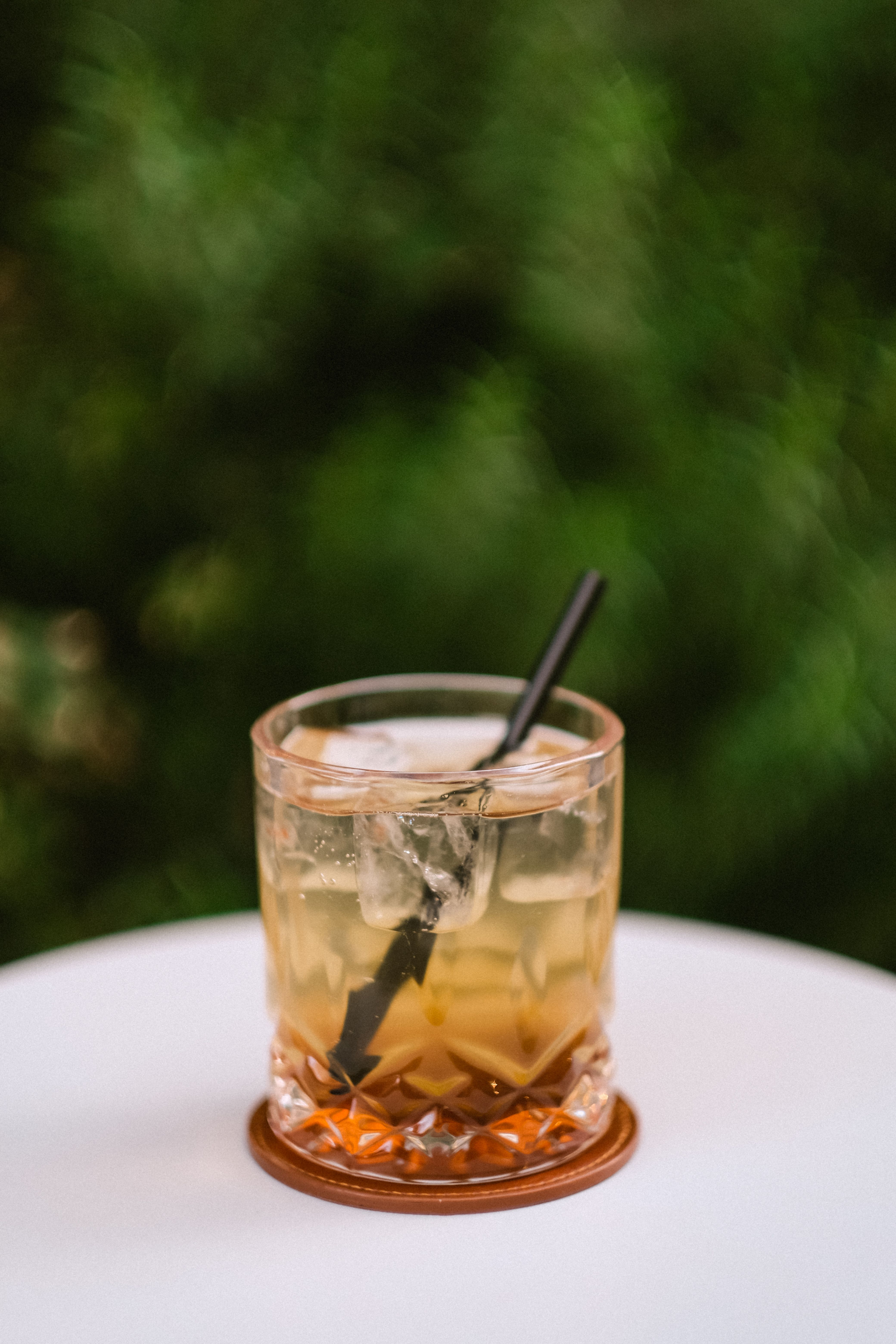 Iced coffee served against soft green cafe plants